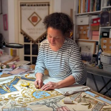 Nathalie Genest est train de repositionner les broderies qu'elle a découpé.