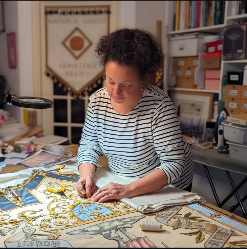 Nathalie Genest est train de repositionner les broderies qu'elle a découpé.